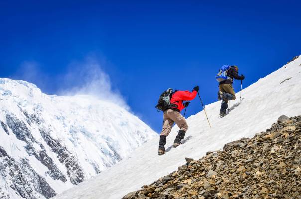Two,Mountain,Backpackers,Walking,On,Snow,With,Peaks,Background,,Himalayas